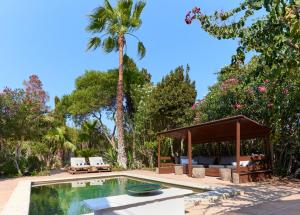 a pool with a gazebo and a palm tree at Can Pardis in Cala Llonga