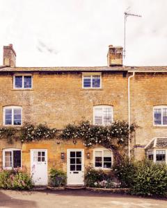una vieja casa de ladrillo con puertas blancas y flores en Middle Rose, en Blockley