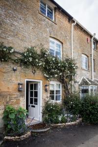 a brick house with a white door and flowers at Middle Rose in Blockley