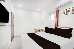 Un dormitorio con una cama blanca con almohadas negras. en Hotel O Century grand luxury rooms, en Warangal