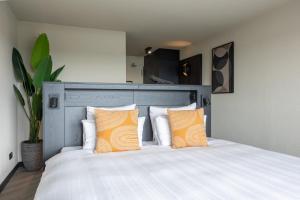 エイマイデンにあるLeonardo Hotel IJmuiden Seaport Beachのベッドルーム1室(オレンジ色の枕2つ、ベッド1台付)