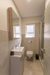 a white bathroom with a sink and a toilet at No 19 at 1 on York - luxury townhouse in George +35 photos