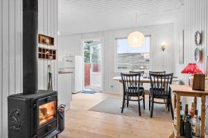 a living room with a stove and a table with chairs at 40363-Juelsminde-Firkanten-1 in Sønderby