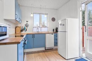 a kitchen with blue cabinets and a white refrigerator at 40363-Juelsminde-Firkanten-1 in Sønderby +28 photos