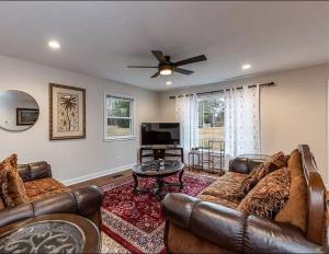 a living room with leather furniture and a flat screen tv at Family Retreat with NEW POOL - Durham Upstairs Unit in Durham