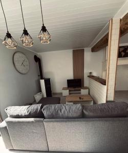 a living room with a couch and a clock at Maison avec petite terrasse cosy 
