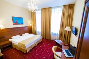 a hotel room with a bed and a desk with a laptop at Agni Club Hotel in Saint Petersburg