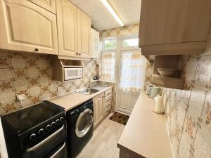 a small kitchen with a washer and a sink at Traditional 3-Bedroom Home- contractors and family in Dartford