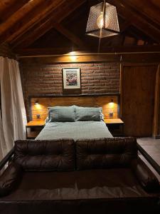 a bedroom with a large bed with a leather couch at el cabure casa de campo in Esquel +7 photos
