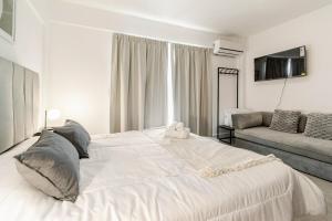 a large white bed in a room with a couch at Vivienda Minimalista Ezeiza 305 in Ezeiza +15 photos