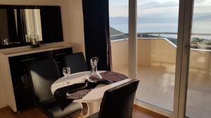 a white table with two wine glasses on it with a balcony at Ohrid Sunset Apartments Velestovo in Ohrid