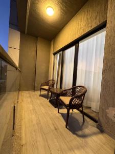 une chambre avec deux chaises, une table et des fenêtres dans l'établissement Tashkent City Apartments E2, à Tachkent