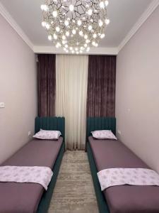 - 2 lits dans une chambre dotée d'un lustre dans l'établissement Tashkent City Apartments E2, à Tachkent