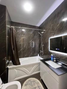 une salle de bain avec une baignoire, des toilettes et un lavabo dans l'établissement Tashkent City Apartments E2, à Tachkent 2 autres photos