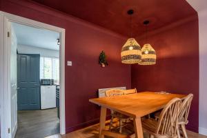 a dining room with a wooden table and a red wall at 1 Hales Orchard in Worcester