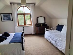 a bedroom with two beds and a window at Fig Tree Cottage in Dursley