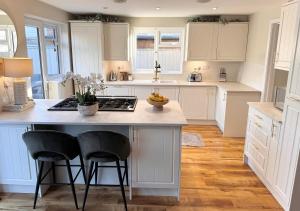 a kitchen with white cabinets and a island with chairs at Seaside retreat in Mudeford in Mudeford