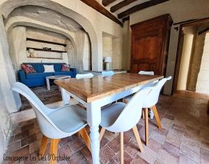 a dining room with a wooden table and white chairs at Le chant du troglodyte in Saumur