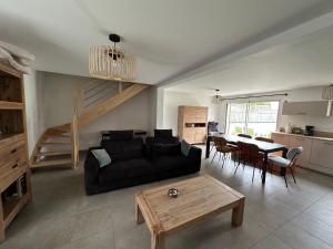 a living room with a black couch and a table at Maison à Dol de Bretagne in Dol-de-Bretagne
