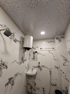 a white bathroom with a sink and a ceiling at Stay Kailash -Vishwanath Temple View in Varanasi