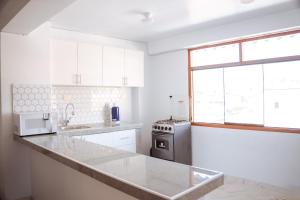 a white kitchen with a sink and a stove at duplex acogedor in Cusco +141 photos