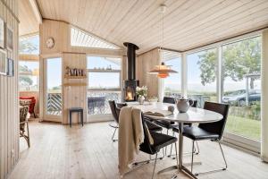 a dining room with a table and chairs and windows at 40353-Juelsminde-Niels-Rasmussens-Vej-127 in Sønderby
