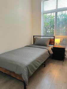 Modern 3-Bedroom Apartment in UBC في فانكوفر: غرفة نوم بها سرير ومصباح ونافذة