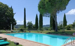 a swimming pool in a park with trees at La Brocca di Valdichiascio in Gubbio