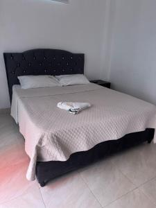 a bed with a black headboard and a towel on it at HOTEL GRAN ESTACION FLORENCIa in Florencia
