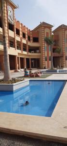 une piscine devant un immeuble avec des palmiers dans l'établissement Luxury 3 bed room apartment in rehab october city compound - modern open view luxury stay, à ‘Ezbet `Abd el-Ḥamîd