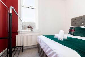 a bedroom with a bed with a green blanket and a window at The Maple Haven – Spacious 3BR with FREE Parking in Jarrow