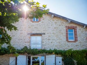 a stone house with windows and vines at Domaine de Vadel in Veilhes