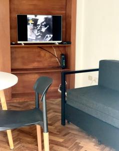 a bedroom with a bed and a chair and a tv at Departamento Moreno in Rosario