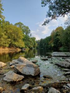 a river with rocks in the water and trees at Cottage near Clisson in Gétigné