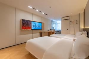 a white bedroom with two beds and a flat screen tv at Huahang Hotel - Guangzhou Baiyun International Airport - Free airport shuttle bus in Guangzhou