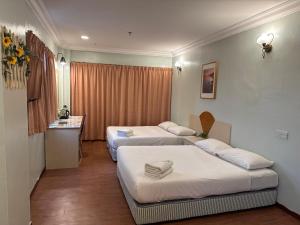a hotel room with two beds and a window at Fair Park Hotel in Ipoh