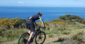 a person riding a bike on a hill near the ocean at Villetta Grazia in Capoliveri +65 photos