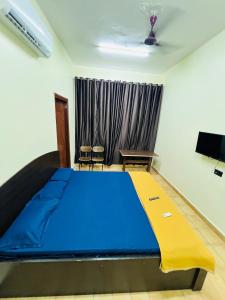 a bedroom with a large blue bed and a tv at HOTEL GARDEN ViEW in Panaji