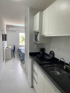 a kitchen with white cabinets and a sink and a bed at Apart Hotel Marinas Tamandaré - apt 304 in Tamandaré