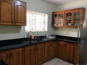a kitchen with wooden cabinets and a stainless steel refrigerator at Agapantha Cottage in Mandeville