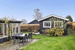uma mesa e cadeiras num quintal com uma casa em 30462-Odder-Kirkeager-7 em Odder