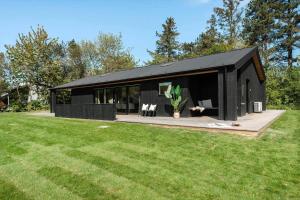a black house with a black roof on a yard at 30333-Odder-Violvej-6 in Odder
