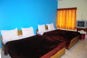 twee bedden in een kamer met een tv bij Hotel Zaraa in Ooty