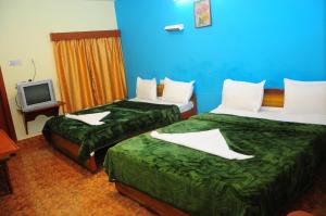 een hotelkamer met twee bedden en een tv bij Hotel Zaraa in Ooty