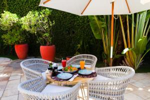 uma mesa com comida com cadeiras e um guarda-sol em Hotel Areias Belas em Maragogi