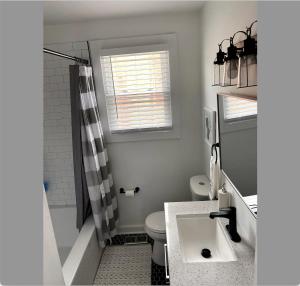 Un baño con lavabo, inodoro y ventana. en Let's Get Cozy In Nashville!, en Nashville