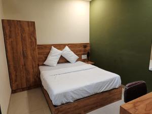una camera da letto con un letto con lenzuola e cuscini bianchi di Glitz Hotels-Mumbai Inn-Saki Naka Junction a Mumbai