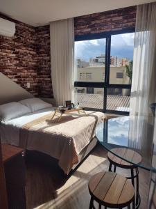 una camera da letto con un letto e due tavoli e una grande finestra di Studio Silva Jardim - Próx Shop Estação com VAGA a Curitiba