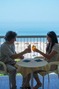 a man and woman sitting at a table on a balcony at Hotel Atlantic in Giulianova