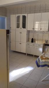 a kitchen with white cabinets and a white tiled floor at Casa completa para 4 pessoas in Itu